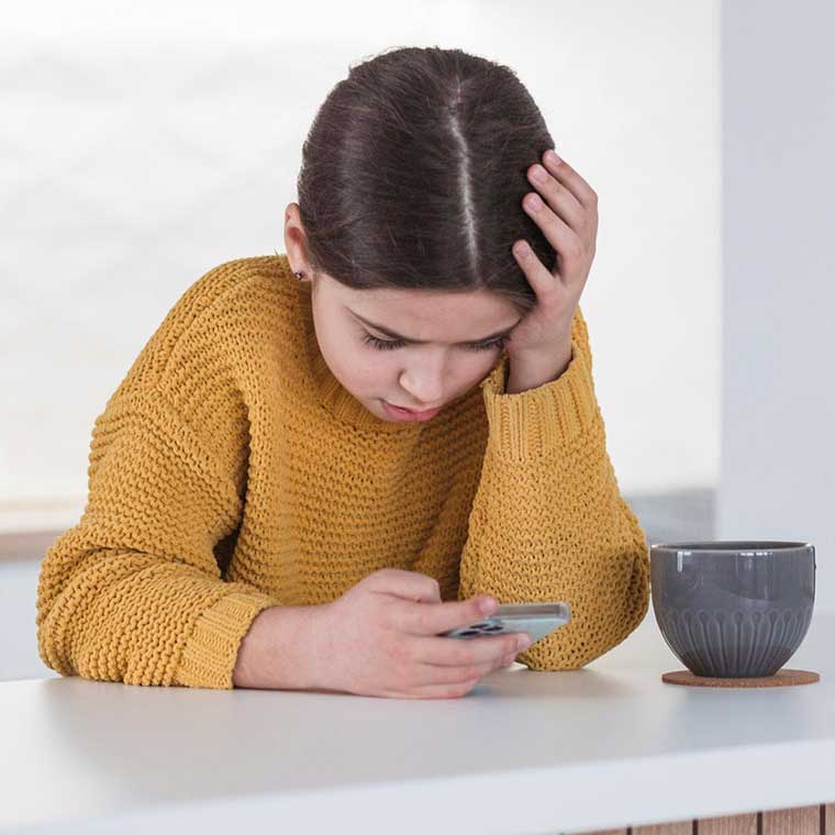 Anak perempuan membaca ponsel dengan cemas memegang kening
